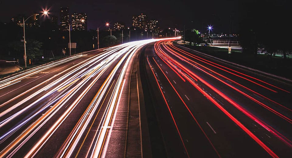Straße mit Verkehrslichter langzeitbelichtet - Lichtstreifen symbolisieren Digitalisierung im Transport